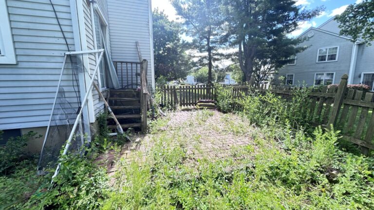 Before renovation view of neglected‑backyard space, uneven ground, old damaged exterior stairs, ready for backyard deck and patio‑renovation in NY‑NJ