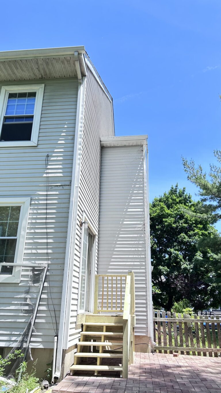 After‑completion photo of finished backyard deck and patio renovation, newly‑built exterior wooden stairs and paved patio, NY‑NJ home remodeling after‑and‑before project